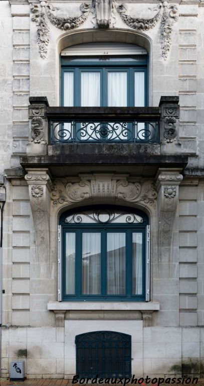 Façade composite avec la fenêtre du bas  complètement éclectique, tout comme le balcon. Seul le décor végétal réaliste de la fenêtre du haut est néoclassique. Tout comme les pilastres évoqués par des traits de refend.