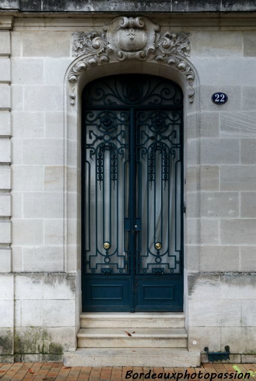 La porte est éclectique ainsi que  l’écusson qui la surmonte. Le décor réaliste de roses est néoclassique.
