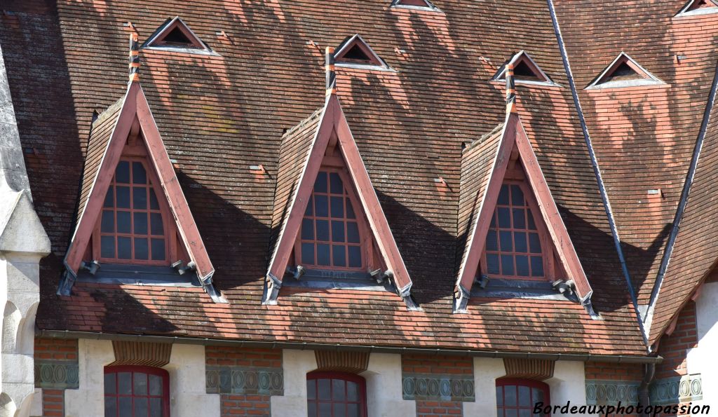 Un toit très pentu avec de petites tuiles plates inconnues dans la région. Des diagonales pour ces fenêtres originales.