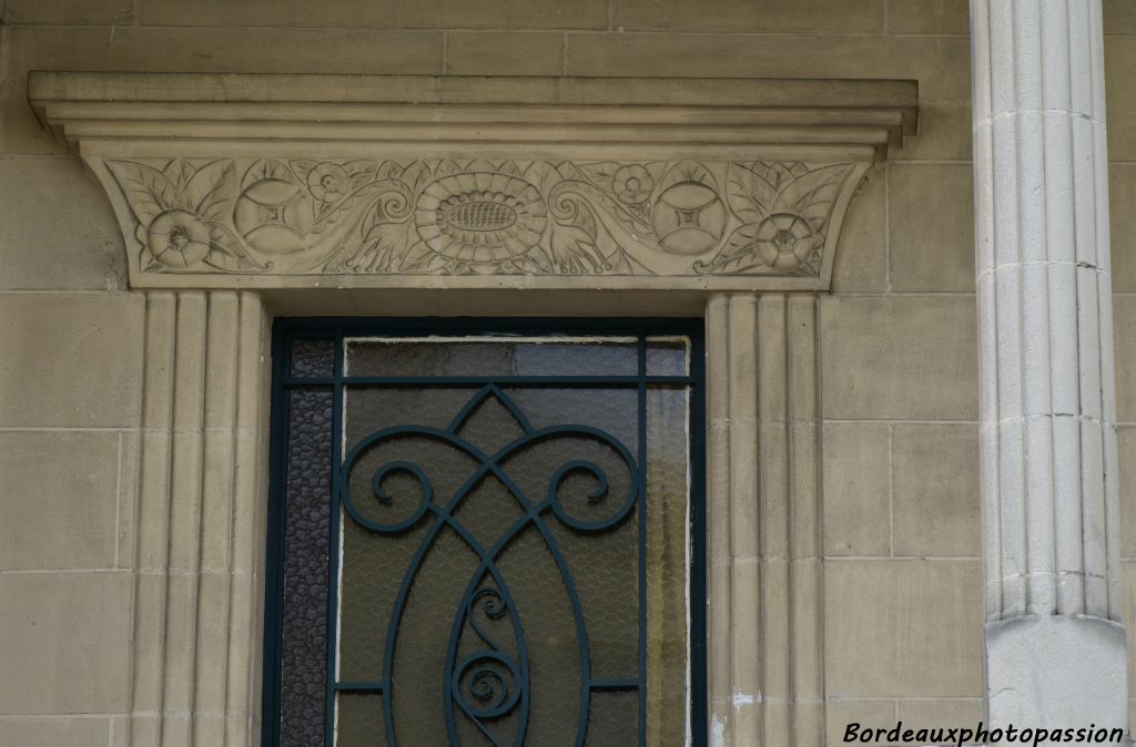 La porte en fer forgé est mise en évidence par un linteau décoré et des côtés rainurés.