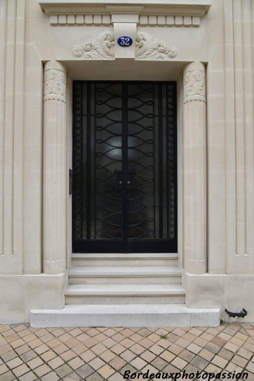 Porte encadrée par deux colonnes à facettes terminées par des chapiteaux cylindriques de fleurs stylisées.
