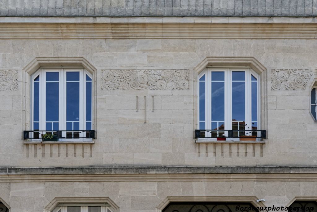 Le premier étage marqué par un bandeau simple, est décoré  d'un fronton canelé, d'une frise simple et surtout de trois méplats de fleurs stylisées.