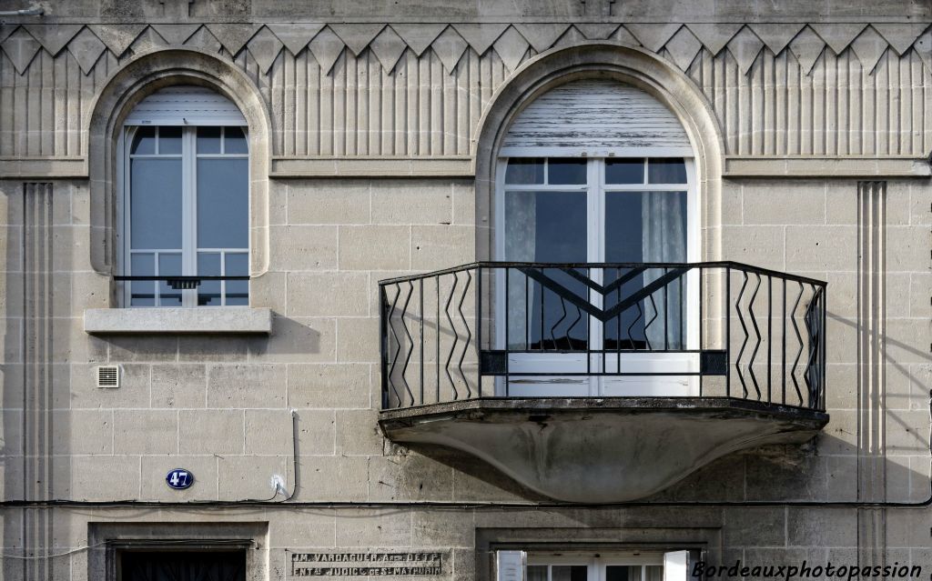 Large balcon avec ferronnerie géométrique simple. Large frise décorative géométique.