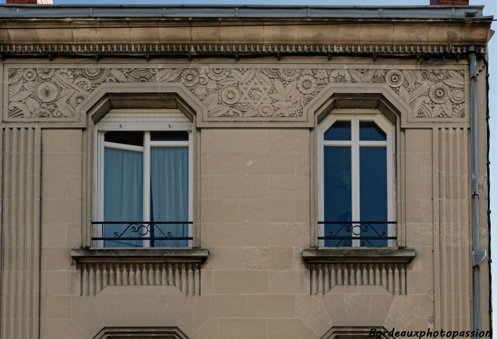 Pilastres rainurés, frise de denticules et large décor en méplat pour la partie supérieure de cet immeuble.