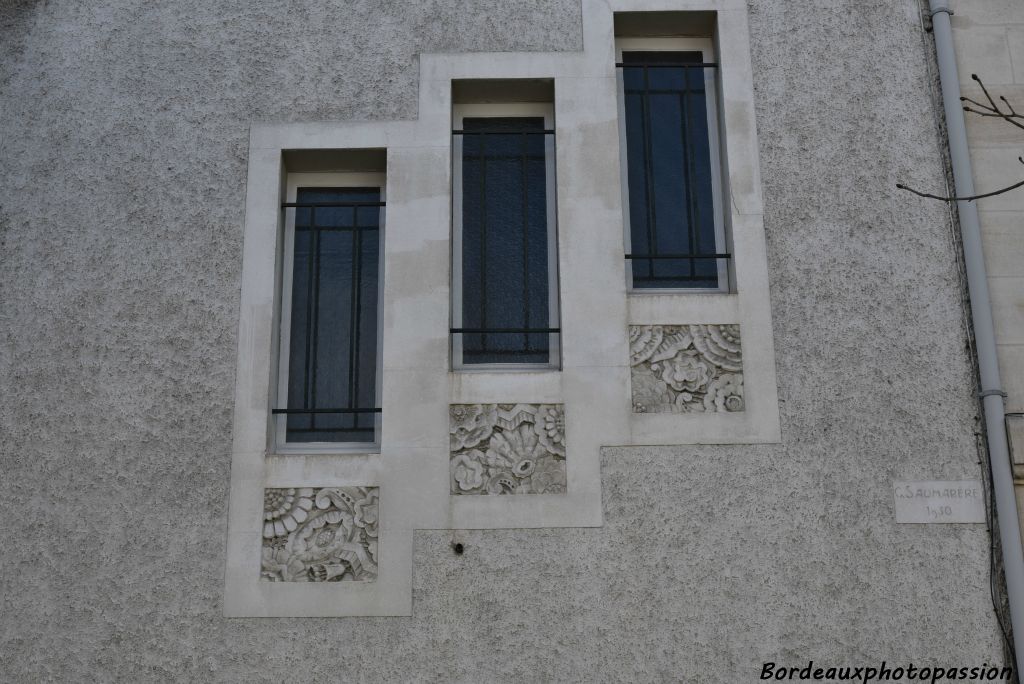 Trio de fenêtres étroites soulignées par des carrés de frise végétale.