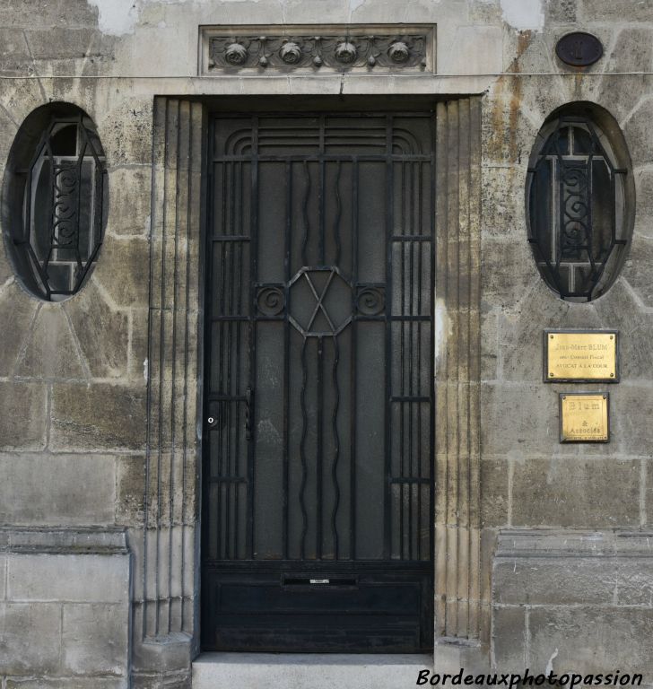 La porte avec pergola est encadrée par deux oculus ovales.