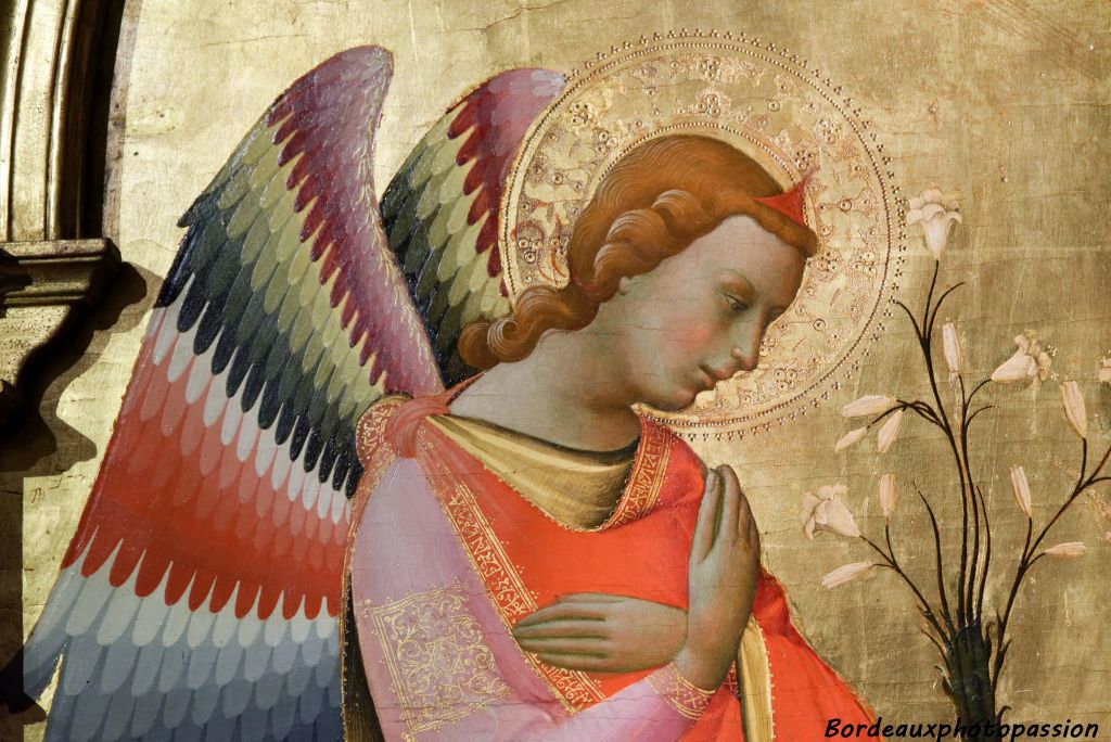 L'archange Gabriel aux ailes de couleurs vives, les bras croisés sur la poitrine s'agenouille devant la Vierge et lui annonce qu'elle portera le fils de Dieu.